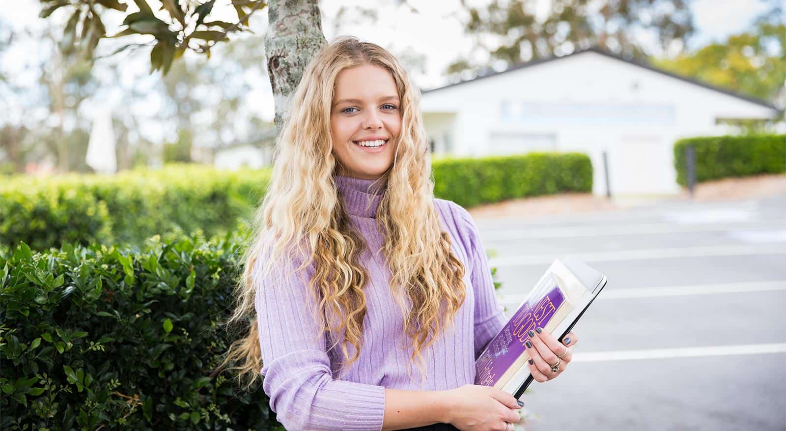 girl in purple holding study books