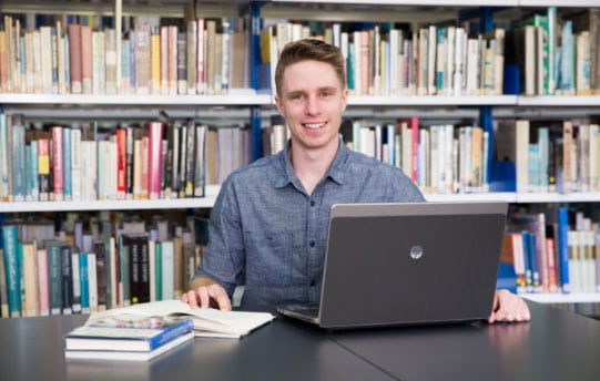 young man on laptop in library